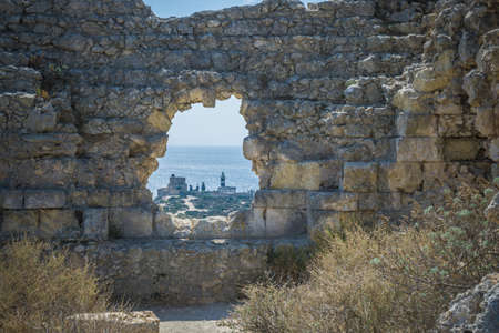 View of lighthouse through hole in stone wall, Cagliari, Masua, Sardinia, Italy