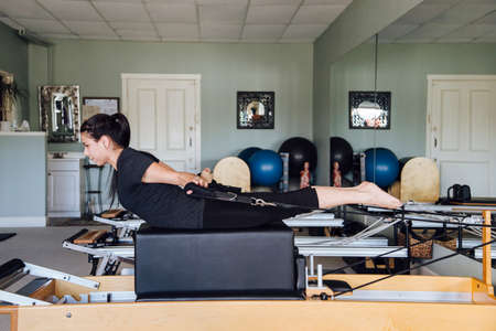 Side view of woman in gym using pilates reformerの写真素材