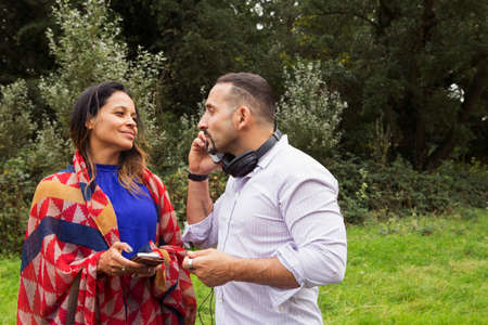 Mature couple outdoors, using smartphones