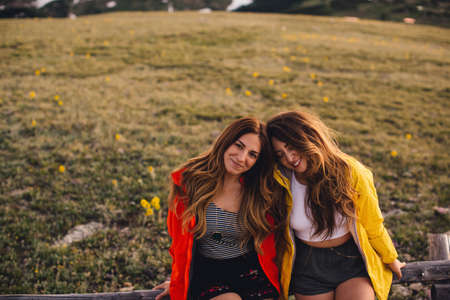 Friends sitting side by side looking at camera smiling, Rocky Mountain National Park, Colorado, USA