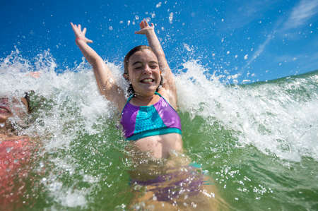 Girls jumping with joy in ocean waveの写真素材