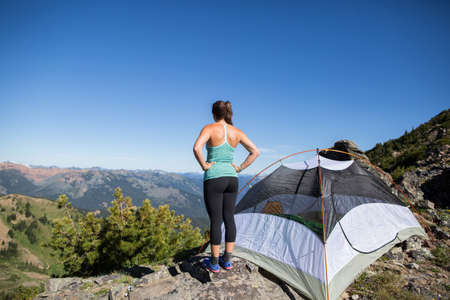Hiker enjoying view beside tent on hilltop, Enchantments, Alpine Lakes Wilderness, Washington, USAの写真素材
