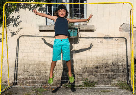 Boy in football goal jumping in mid airの写真素材