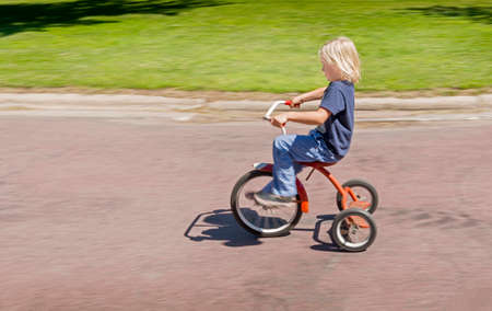 Side view of boy riding tricycleの写真素材