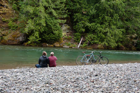 Rear view of couple on riverbank looking away, Packwood, Washington, USA