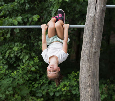 Girl hanging upside down from monkey bar