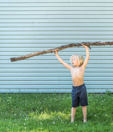 Boy with arms raised holding stickの写真素材
