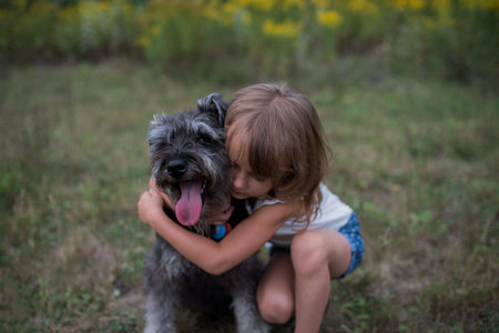 Little girl hugging pet dog on grass fieldの写真素材