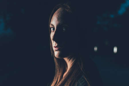 Portrait of young freckled woman with nose piercing at nightの写真素材