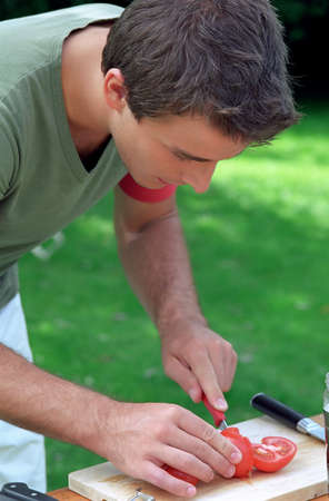 Young male chopping tomatoesの写真素材