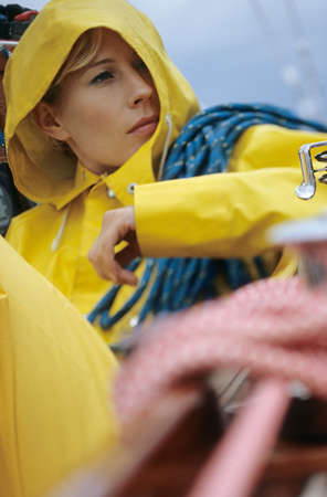 Woman in yellow raincoat carrying ropeの写真素材