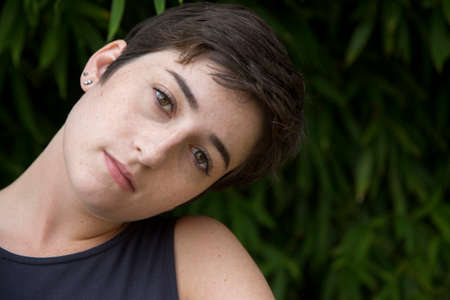 Portrait of young woman with cropped hair, outdoors, pensive expression