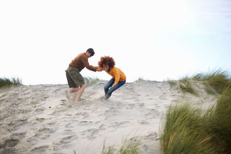 Couple playing at top of sand duneの写真素材