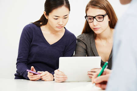 Two young women using digital tabletの写真素材