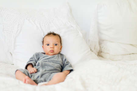 Baby sitting up on bedの写真素材