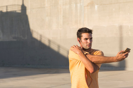 Male athlete listening to music and stretching, Van Nuys, California, USAの写真素材