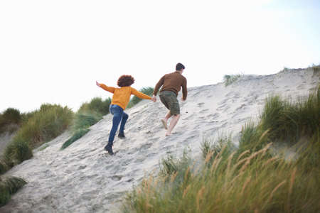 Couple racing up to top of sand duneの写真素材