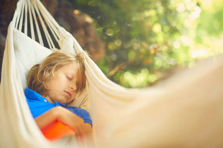 Cute boy reclining in garden hammock asleepの写真素材