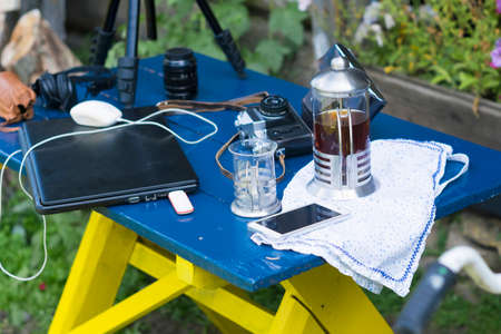 Camera equipment, laptop and cafetiere on table in gardenの写真素材