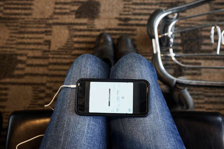 Personal perspective of smartphone on woman's knees in airport lounge