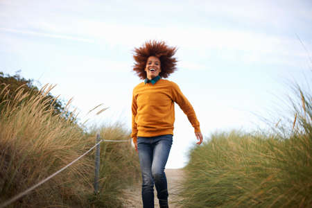 Woman running down grassy duneの写真素材