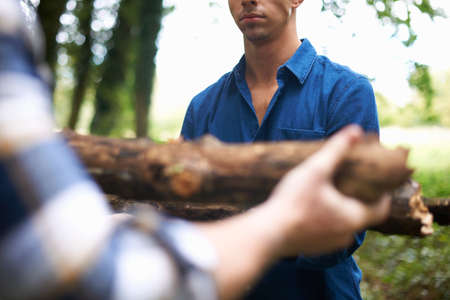Cropped view of man handing friend firewoodの写真素材