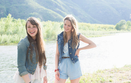Two female friends on riverbank, Piemonte, Italyの写真素材