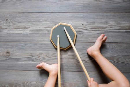 Overhead cropped view of boy sitting on wooden floor drummingの写真素材