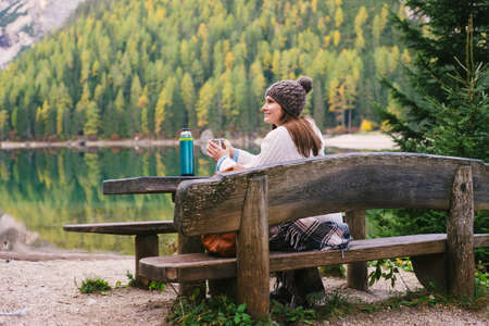 Woman relaxing on park bench, Lago di Braies, Dolomite Alps, Val di Braies, South Tyrol, Italy