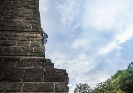 Low angle view of boy climbing stone wallの写真素材