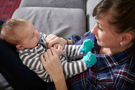 Mother sitting on sofa looking at baby boy, smiling
