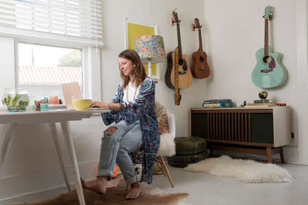 Woman sitting at dining table using laptop