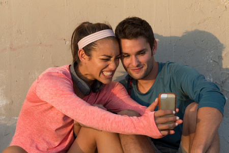 Couple taking selfie in front of concrete wallの写真素材