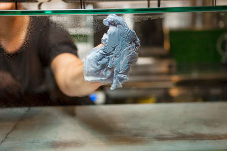 Woman's hand cleaning display case glass in cafeの写真素材