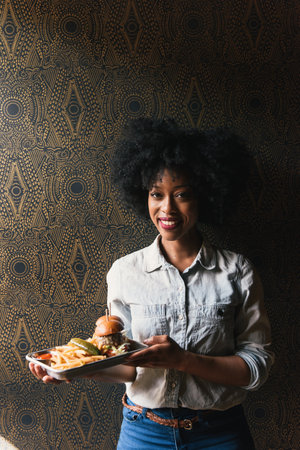 Woman holding plates of burger and french fries