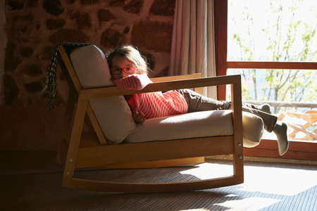 Portrait of young girl lying on rocking chairの写真素材