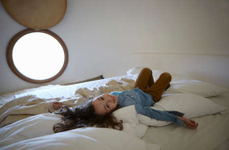 Candid portrait of girl lying on bedの写真素材