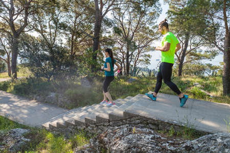 Male and female runners running down park stairway, Split, Dalmatia, Croatiaの写真素材