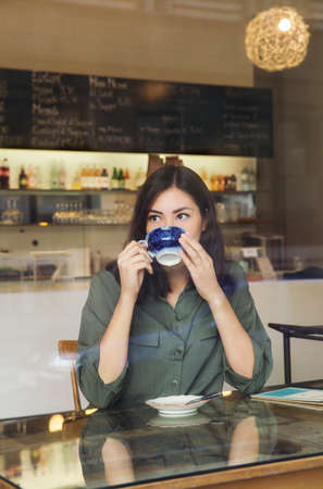 Woman drinking coffee in cafeの写真素材