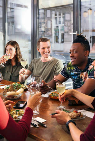 Group of friends enjoying meal in restaurantの写真素材