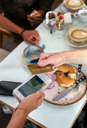 Close-up of man paying with credit card in restaurantの写真素材