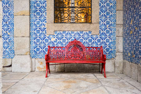 Portugal, Porto, Red bench in front of wall covered with azulejosの写真素材