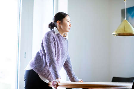 Pensive woman standing at table