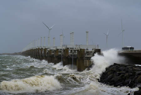Netherlands, Vrouwenpolder, Sea waves crashing against pier during storm Corrieの写真素材