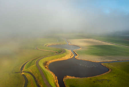 Netherlands, Sint Maarten, Aerial view of dykes and ponds in fields in fogの写真素材