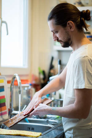 Man washing dishes in kitchenの写真素材