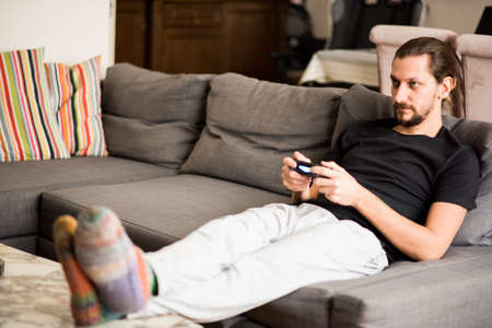 Man on sofa playing video game at homeの写真素材