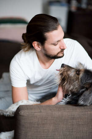Man petting dachshund on sofa