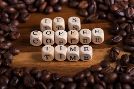 it's coffee time with a wooden and beans coffee all around on a wooden table on close up. aroma of fresh coffee.の写真素材
