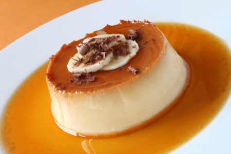 A banana creme caramel decorated with banana slices and chocolate shavings の写真素材